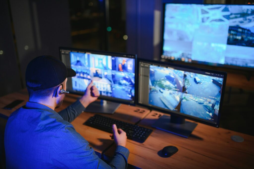 Male security guard monitoring modern CCTV cameras indoors