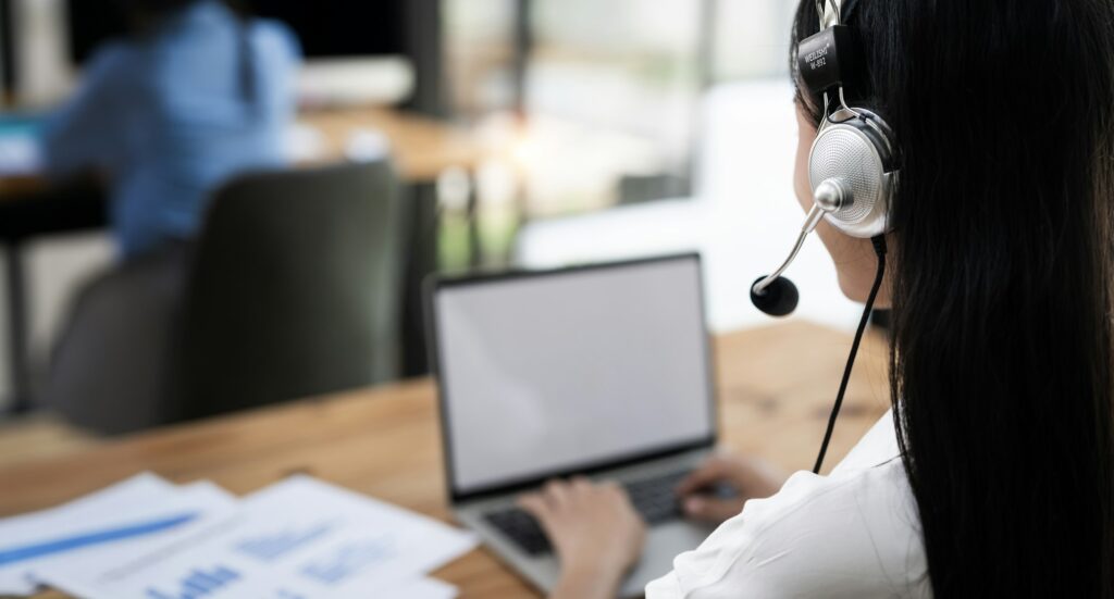 Rear view of Young operator woman agent with headsets working in a call centre.